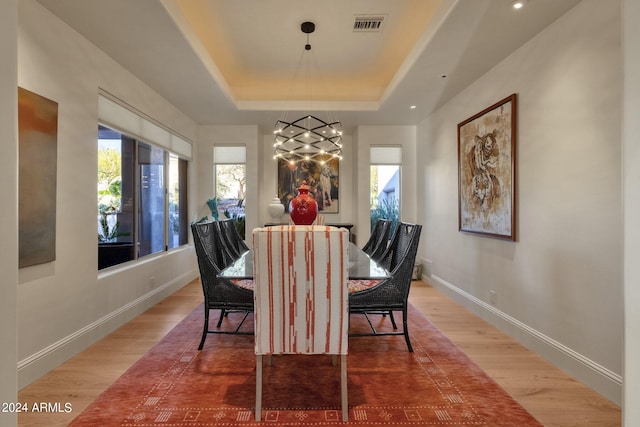 dining area with hardwood / wood-style floors and a tray ceiling