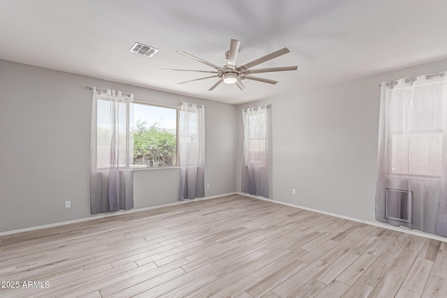 spare room with visible vents, a ceiling fan, baseboards, and light wood-type flooring