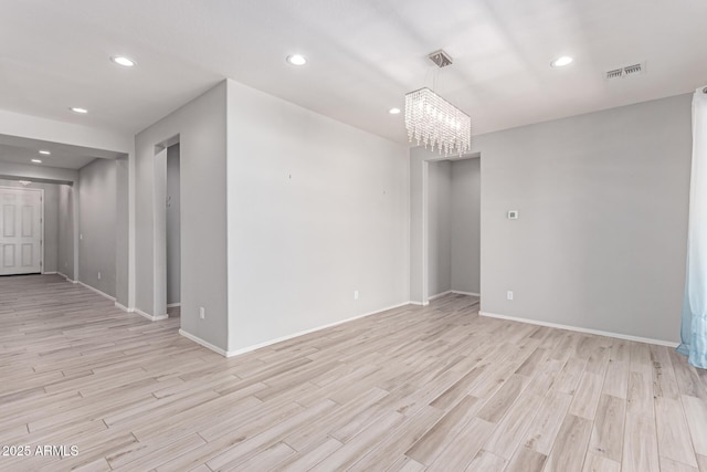 spare room featuring visible vents, light wood-style floors, baseboards, and an inviting chandelier