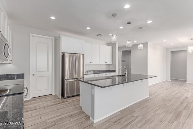 kitchen with white cabinets, appliances with stainless steel finishes, a sink, light wood-style floors, and visible vents
