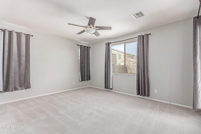 spare room featuring a ceiling fan, baseboards, visible vents, and light carpet