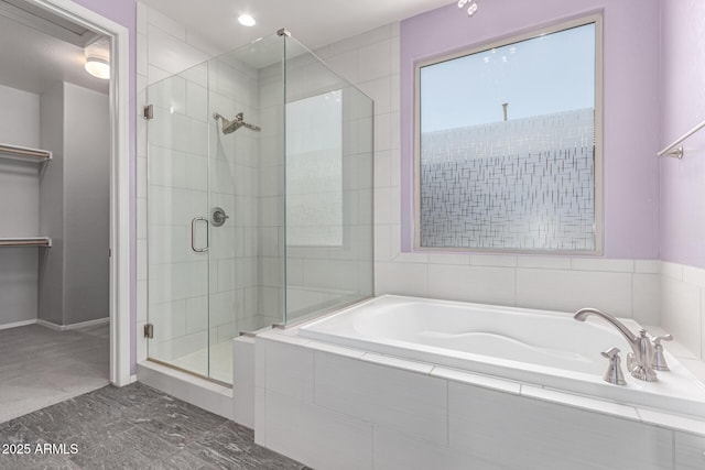 full bath with recessed lighting, a spacious closet, a shower stall, and a garden tub