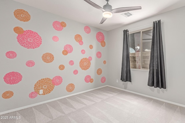 carpeted spare room with baseboards, ceiling fan, and visible vents