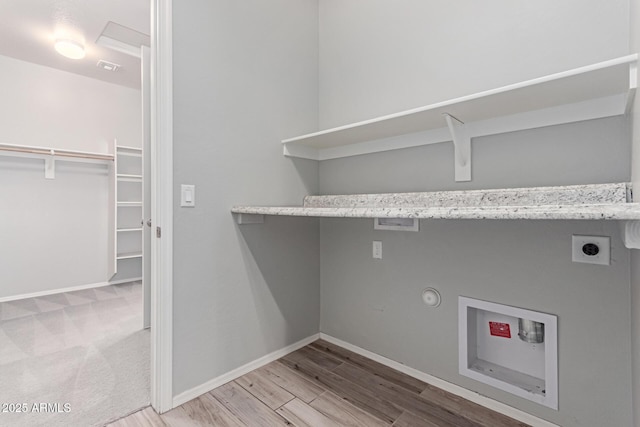 laundry area featuring baseboards, electric dryer hookup, and wood finished floors