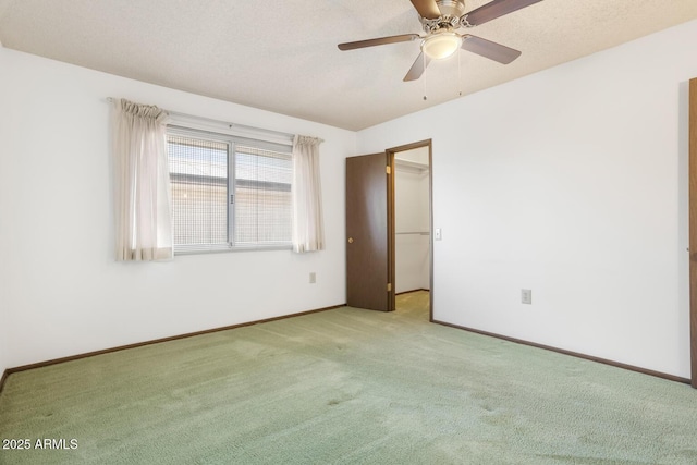 carpeted empty room featuring ceiling fan and a textured ceiling