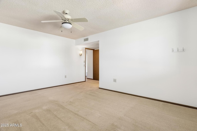 spare room with ceiling fan, light carpet, and a textured ceiling