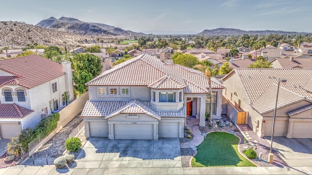 mediterranean / spanish-style home featuring stucco siding, driveway, a mountain view, a residential view, and a tiled roof