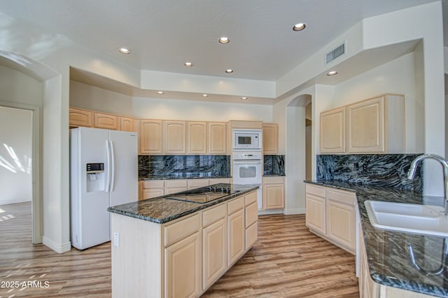 kitchen featuring white appliances, light brown cabinets, visible vents, a sink, and light wood-type flooring