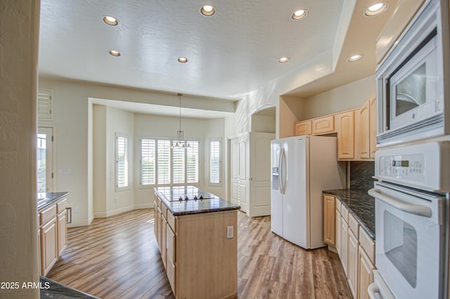 kitchen featuring light wood-type flooring, white appliances, an inviting chandelier, and light brown cabinets