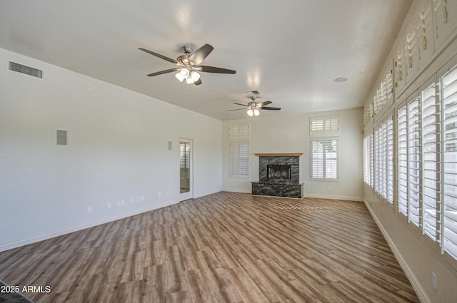 unfurnished living room with visible vents, baseboards, ceiling fan, a fireplace, and wood finished floors