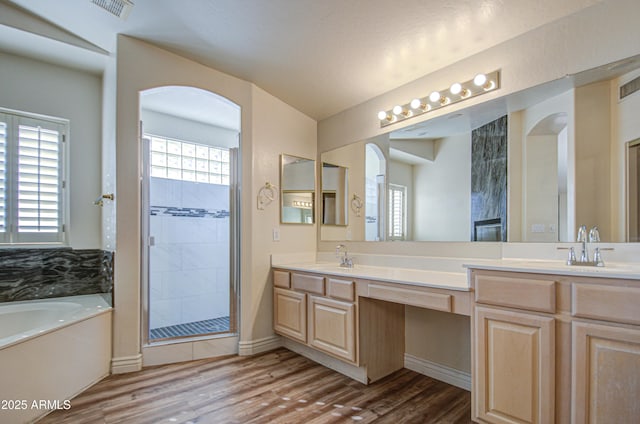 full bath with visible vents, a garden tub, a stall shower, wood finished floors, and double vanity