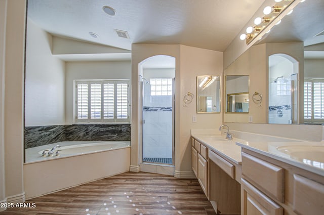 full bathroom featuring a shower stall, a garden tub, double vanity, wood finished floors, and a sink