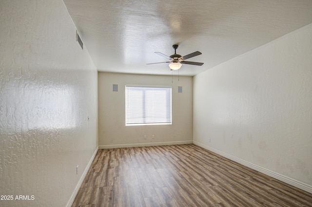 spare room featuring visible vents, wood finished floors, baseboards, and ceiling fan