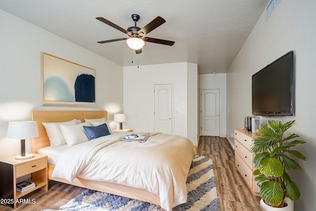 bedroom featuring ceiling fan, visible vents, and light wood-style flooring