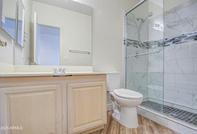 full bath featuring vanity, toilet, wood finished floors, and a shower stall