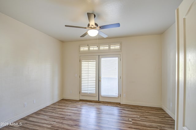 unfurnished room with baseboards, wood finished floors, and a ceiling fan