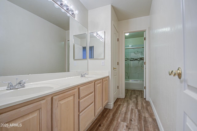 bathroom featuring a sink, baseboards, wood finished floors, and double vanity