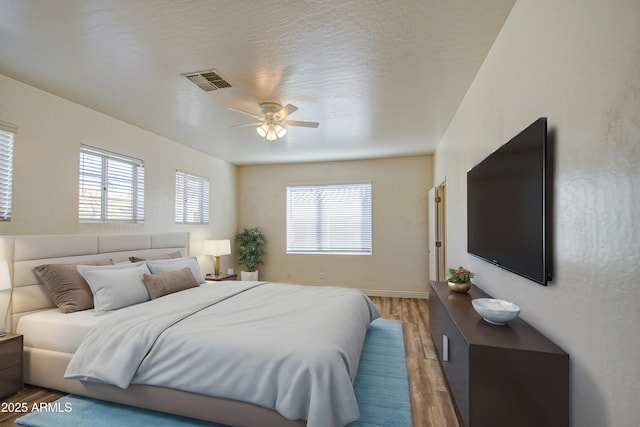 bedroom with visible vents, baseboards, light wood-style floors, and a ceiling fan