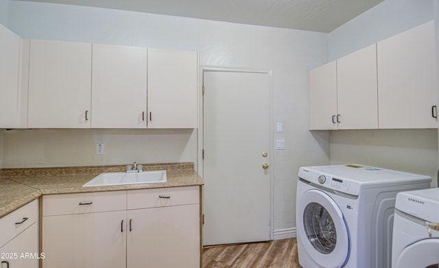 laundry area with cabinet space, washing machine and dryer, light wood-type flooring, and a sink