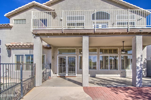 back of property featuring stucco siding, a ceiling fan, a tile roof, a patio, and fence