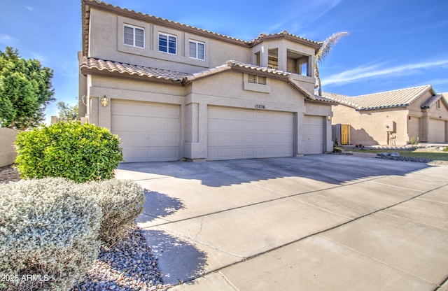 mediterranean / spanish house featuring stucco siding, concrete driveway, an attached garage, and a tiled roof