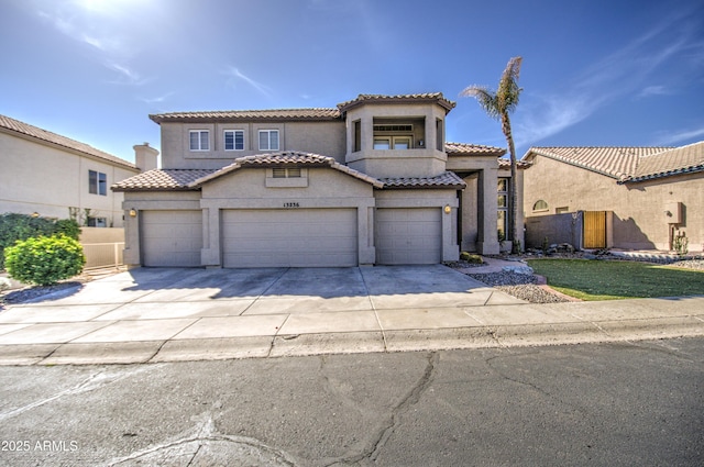 mediterranean / spanish-style home featuring a tile roof, concrete driveway, an attached garage, and stucco siding