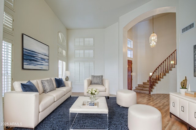 living room featuring visible vents, a high ceiling, an inviting chandelier, wood finished floors, and arched walkways