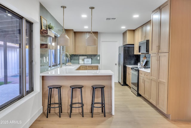 kitchen with visible vents, light wood-style flooring, electric range, and a peninsula