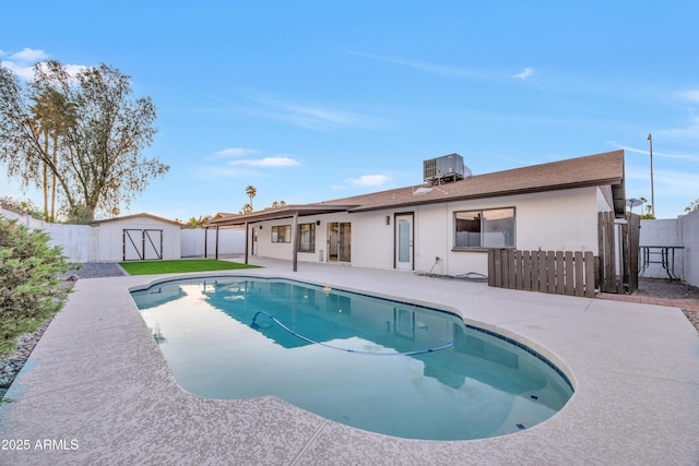 view of swimming pool with a storage unit, an outdoor structure, a fenced backyard, central AC unit, and a patio