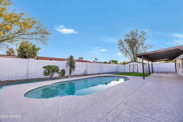 view of swimming pool featuring a storage shed, an outbuilding, a fenced backyard, and a patio area