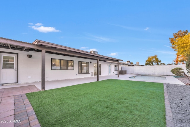 rear view of property with central AC, a fenced backyard, a fenced in pool, a patio, and a yard