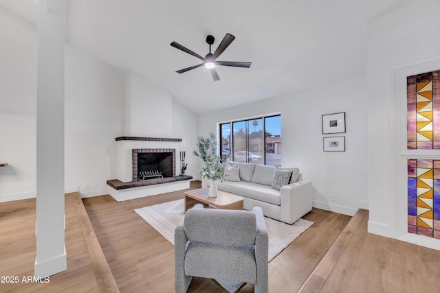 living room with a ceiling fan, a brick fireplace, baseboards, lofted ceiling, and light wood-style floors