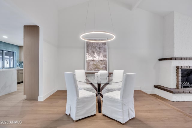 unfurnished dining area featuring a brick fireplace, baseboards, and light wood-style flooring