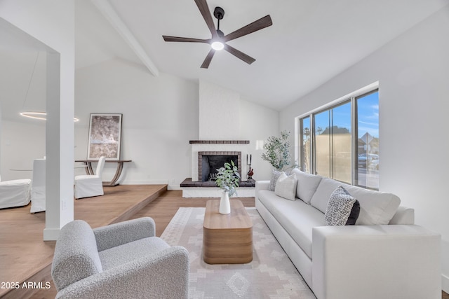 living room with a ceiling fan, a brick fireplace, beam ceiling, high vaulted ceiling, and light wood-style floors