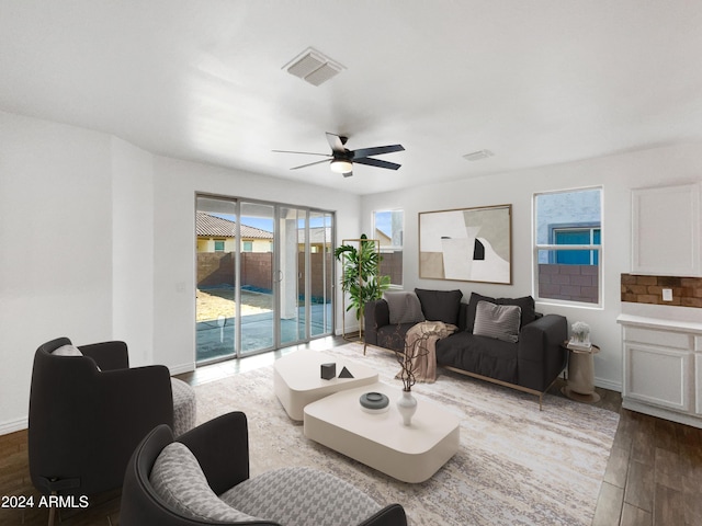 living area with visible vents, ceiling fan, baseboards, and wood finished floors