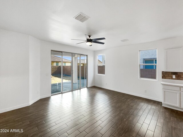 unfurnished living room featuring dark wood-type flooring and ceiling fan