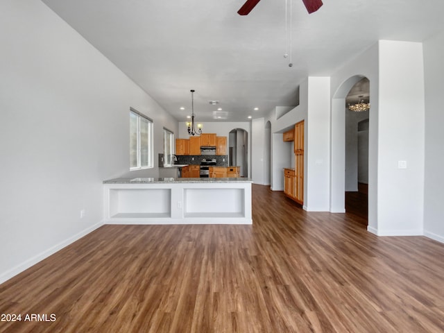 kitchen featuring kitchen peninsula, light stone countertops, dark hardwood / wood-style flooring, stainless steel range with electric stovetop, and ceiling fan with notable chandelier