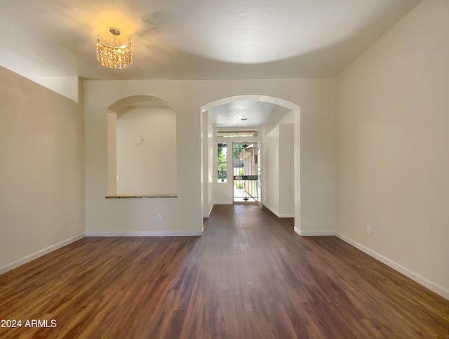 unfurnished room with dark wood-type flooring and an inviting chandelier