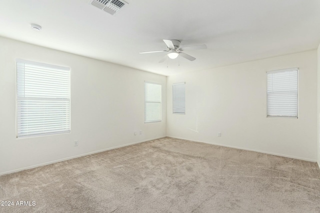 unfurnished room with plenty of natural light, ceiling fan, and light carpet