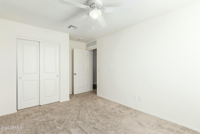 unfurnished bedroom with ceiling fan, light colored carpet, and a closet