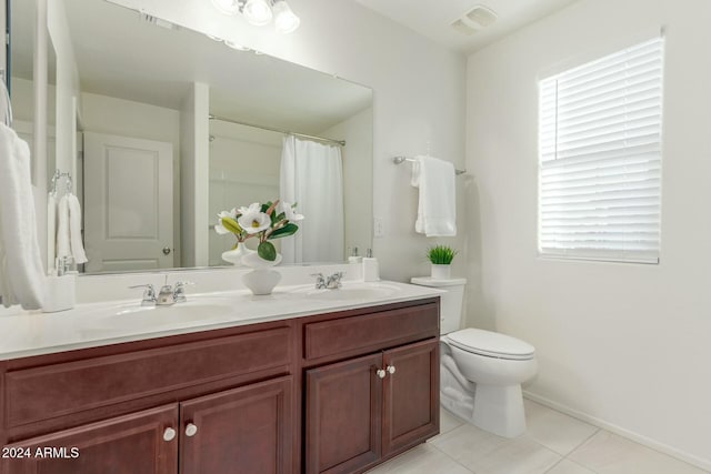 bathroom featuring toilet, vanity, tile patterned floors, and a wealth of natural light