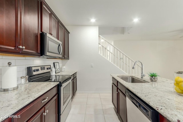 kitchen with light stone countertops, sink, tasteful backsplash, light tile patterned flooring, and appliances with stainless steel finishes