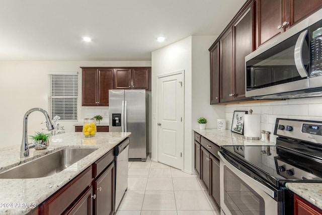 kitchen with decorative backsplash, light stone countertops, sink, and appliances with stainless steel finishes