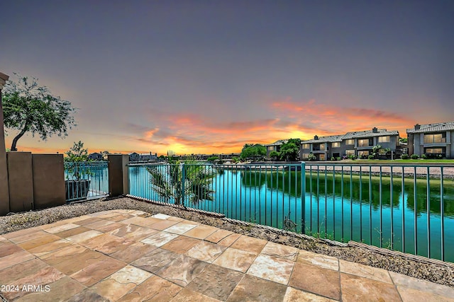 patio terrace at dusk featuring a water view