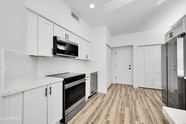 kitchen featuring light hardwood / wood-style floors, stainless steel appliances, light stone countertops, and white cabinets