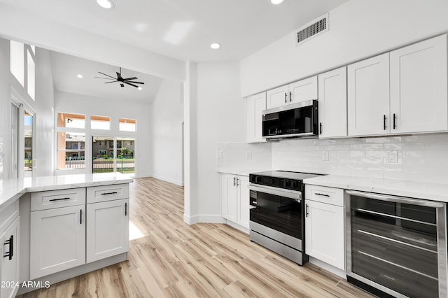 kitchen featuring light hardwood / wood-style flooring, wine cooler, white cabinetry, appliances with stainless steel finishes, and ceiling fan