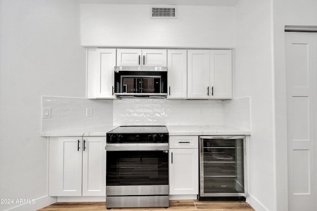 kitchen with white cabinetry, wine cooler, appliances with stainless steel finishes, and light stone counters