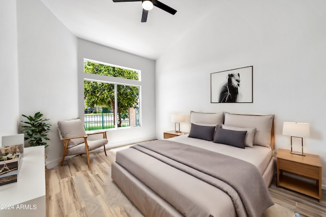 bedroom featuring light hardwood / wood-style floors, vaulted ceiling, and ceiling fan