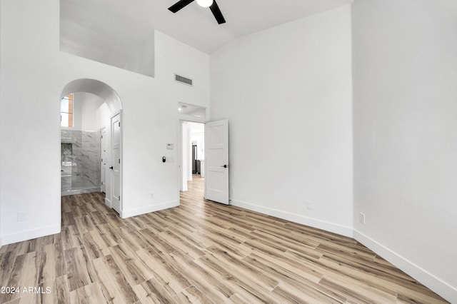 unfurnished bedroom with connected bathroom, light hardwood / wood-style flooring, high vaulted ceiling, and ceiling fan