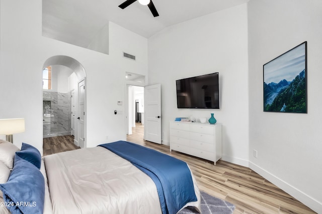 bedroom with connected bathroom, ceiling fan, high vaulted ceiling, and light wood-type flooring